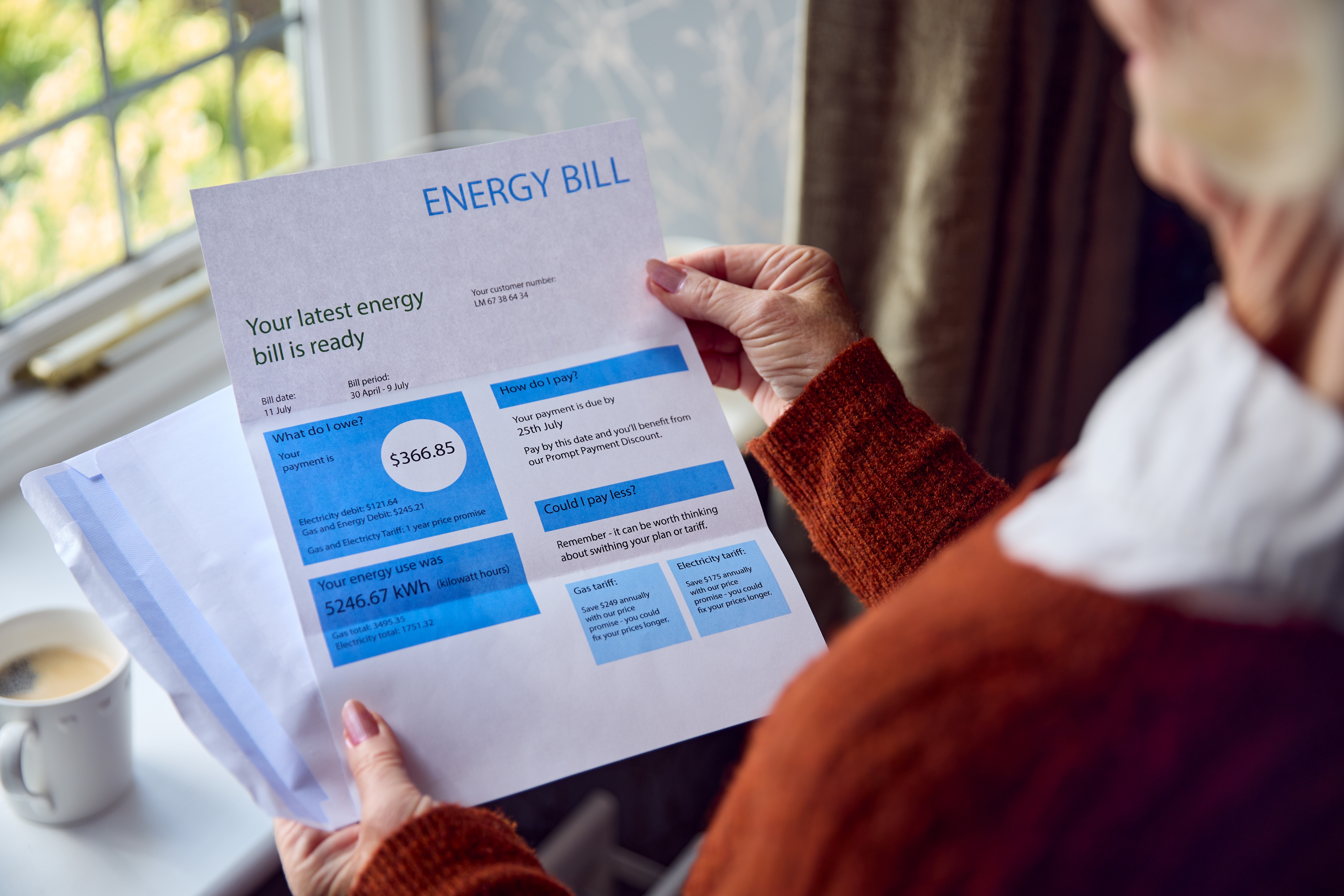 Older female is seen from the side as she looks at an energy bill