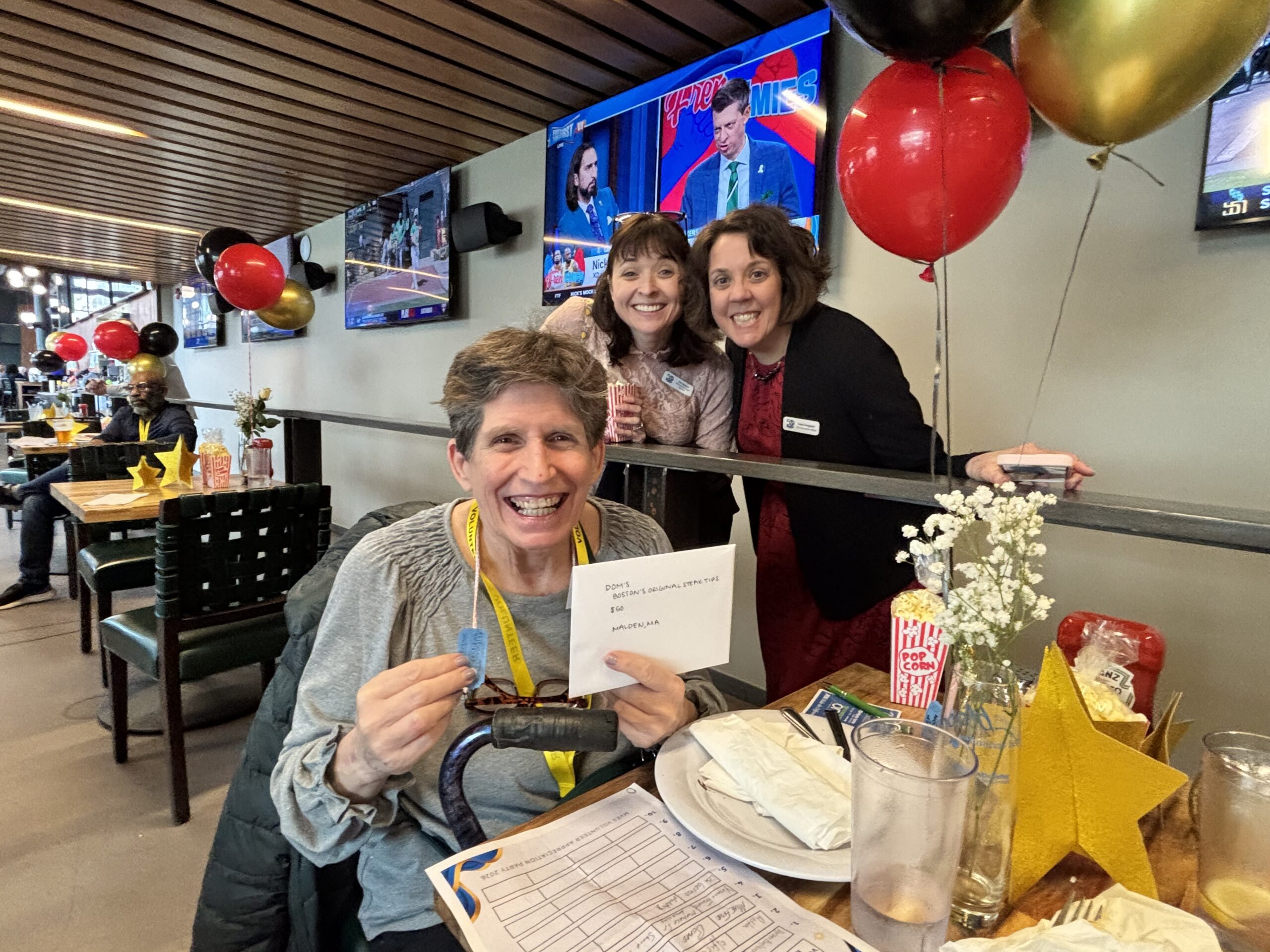3 Photo Apr 16 2026, 5 29 50 PM Volunteer at table holds up winning raffle prize and ticket as two MVES staffers stand smiling behind her.